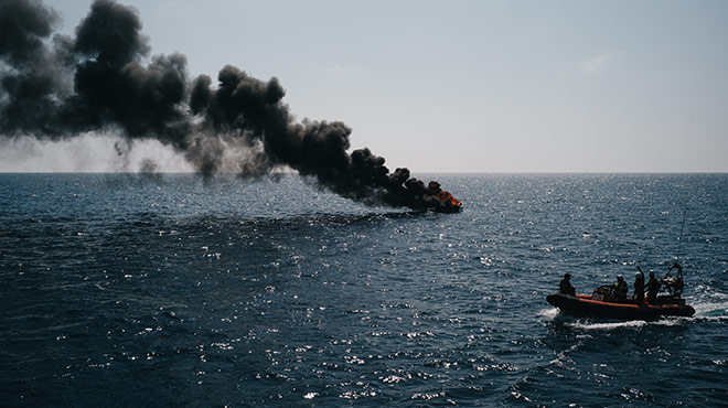 Rettungsboot im Mittelmeer vor brennendem Schlauchboot